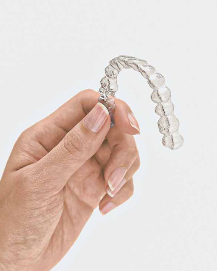 Hand holding invisible aligners
